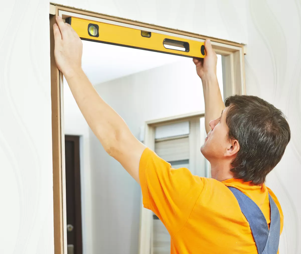 Installer using a level to align door frame