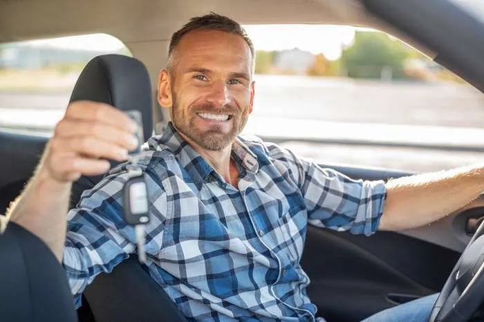 man in a car shows a key