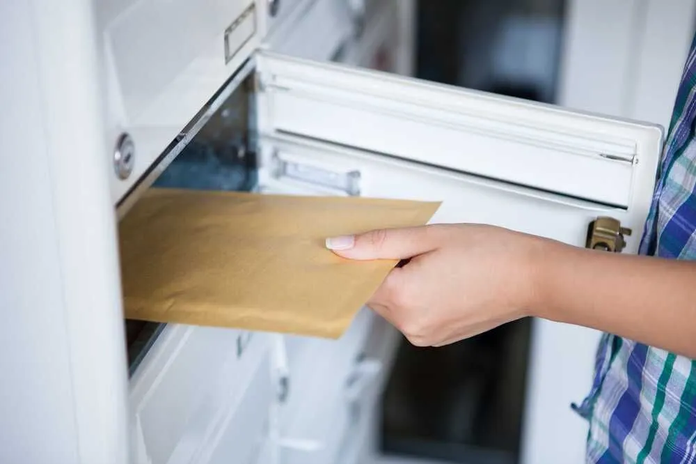 woman takes mail from mailbox