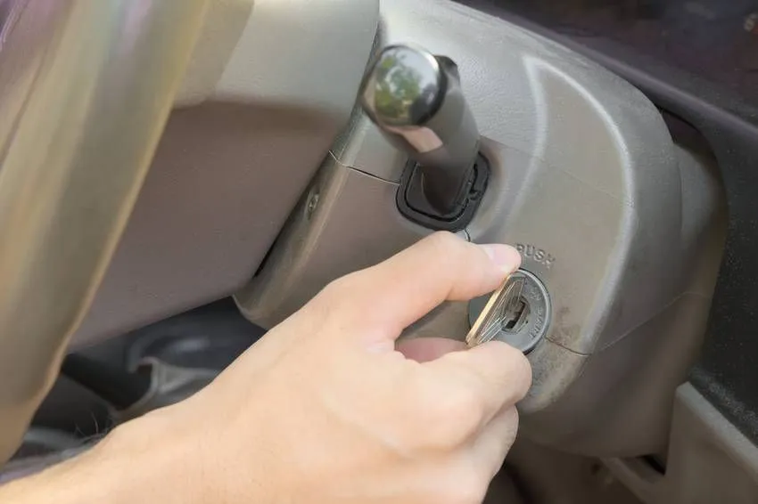 Male hand starting engine of an old style car by using plain silver key
