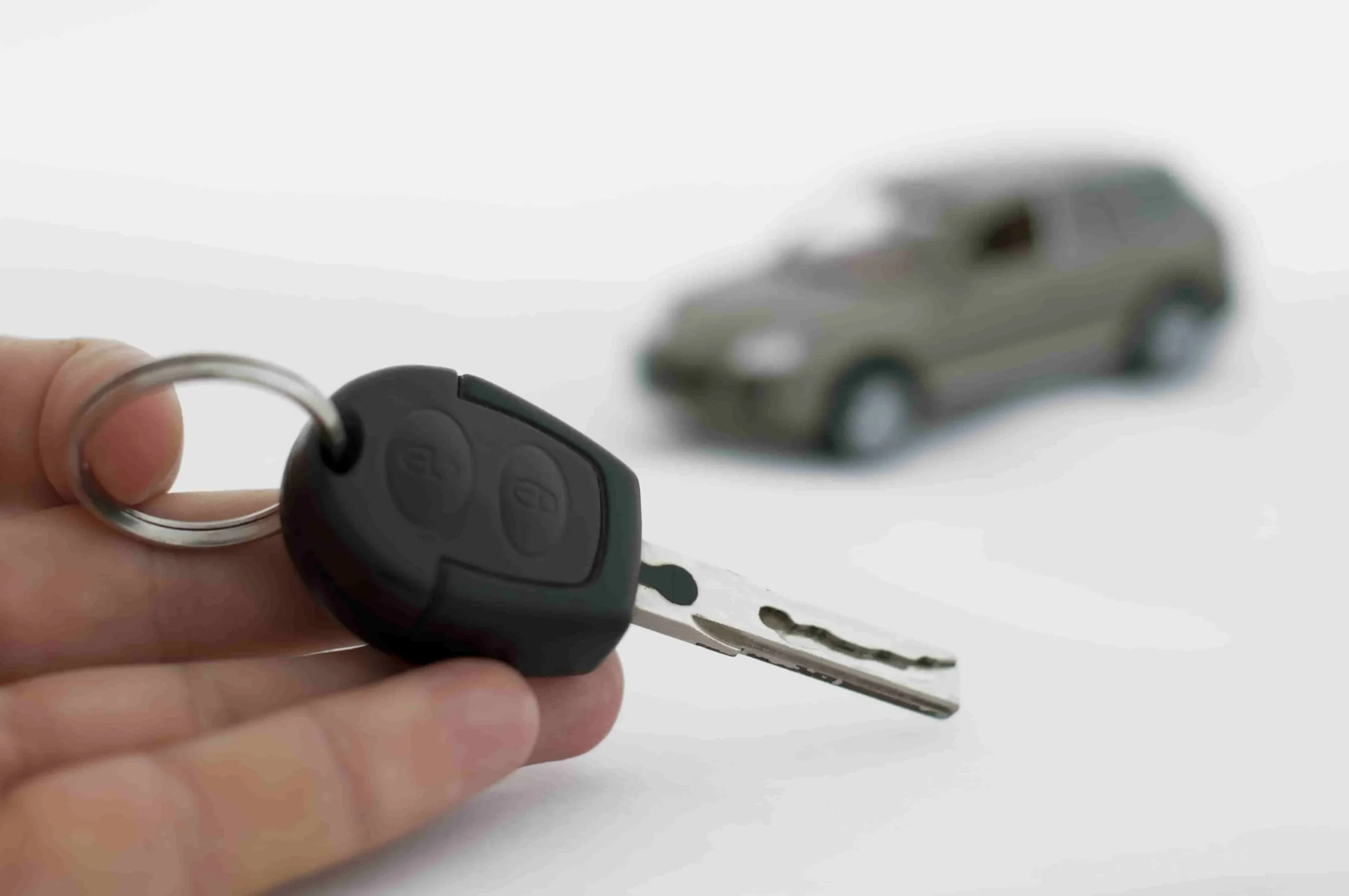 Hand holding keys and a car in the background